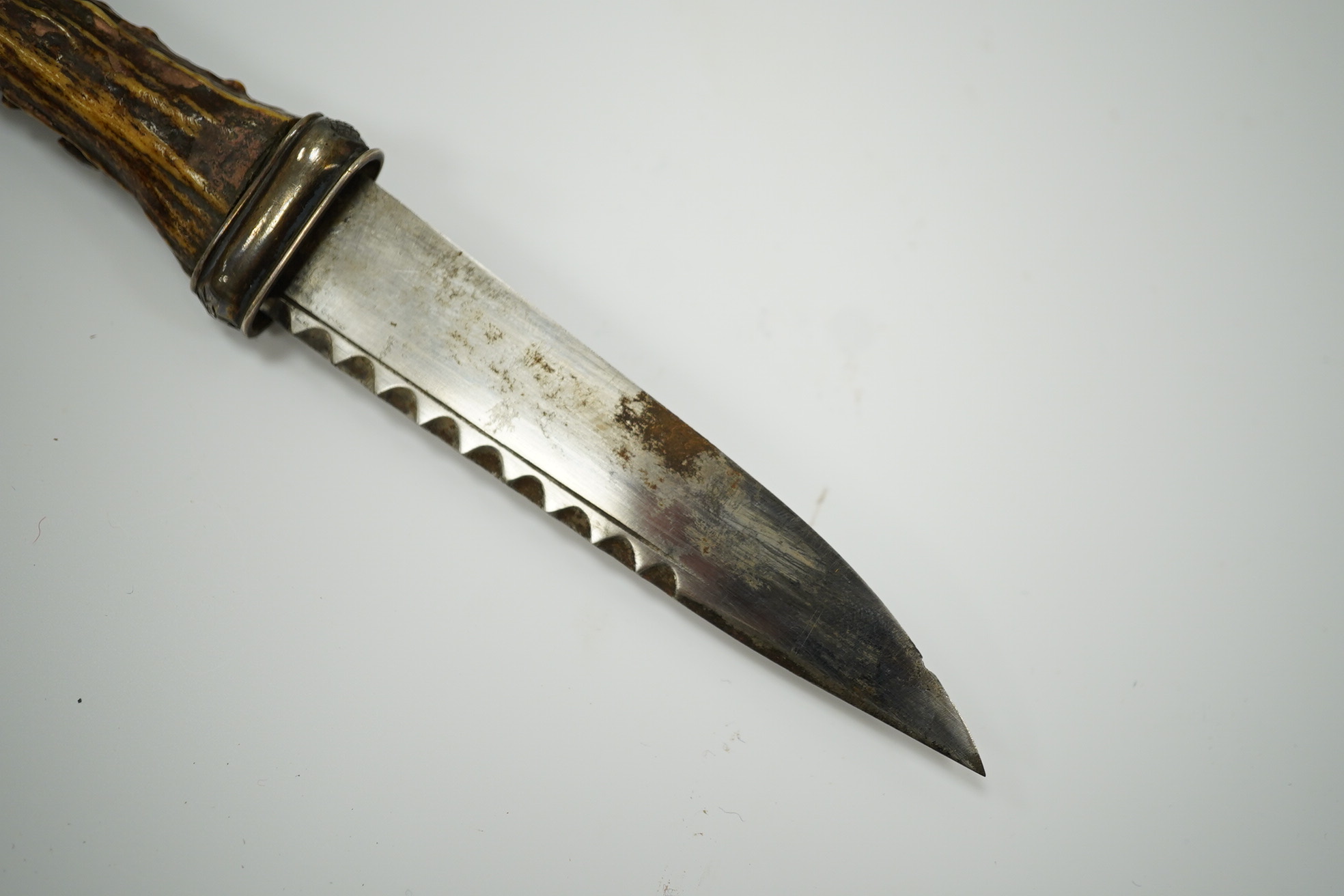 A late 19th century Scottish traditional sgian dubh with foiled glass mounted deer antler handle, and silver coloured metal mounts with thistles in relief, blade 10cm. Condition - fair, missing chape.